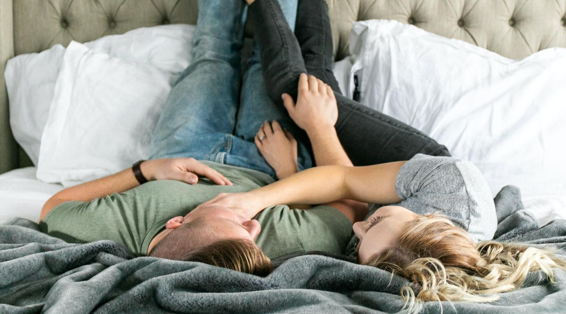 Ein Mann und eine Frau liegen mit hochgelegten Füßen auf einem Bett.