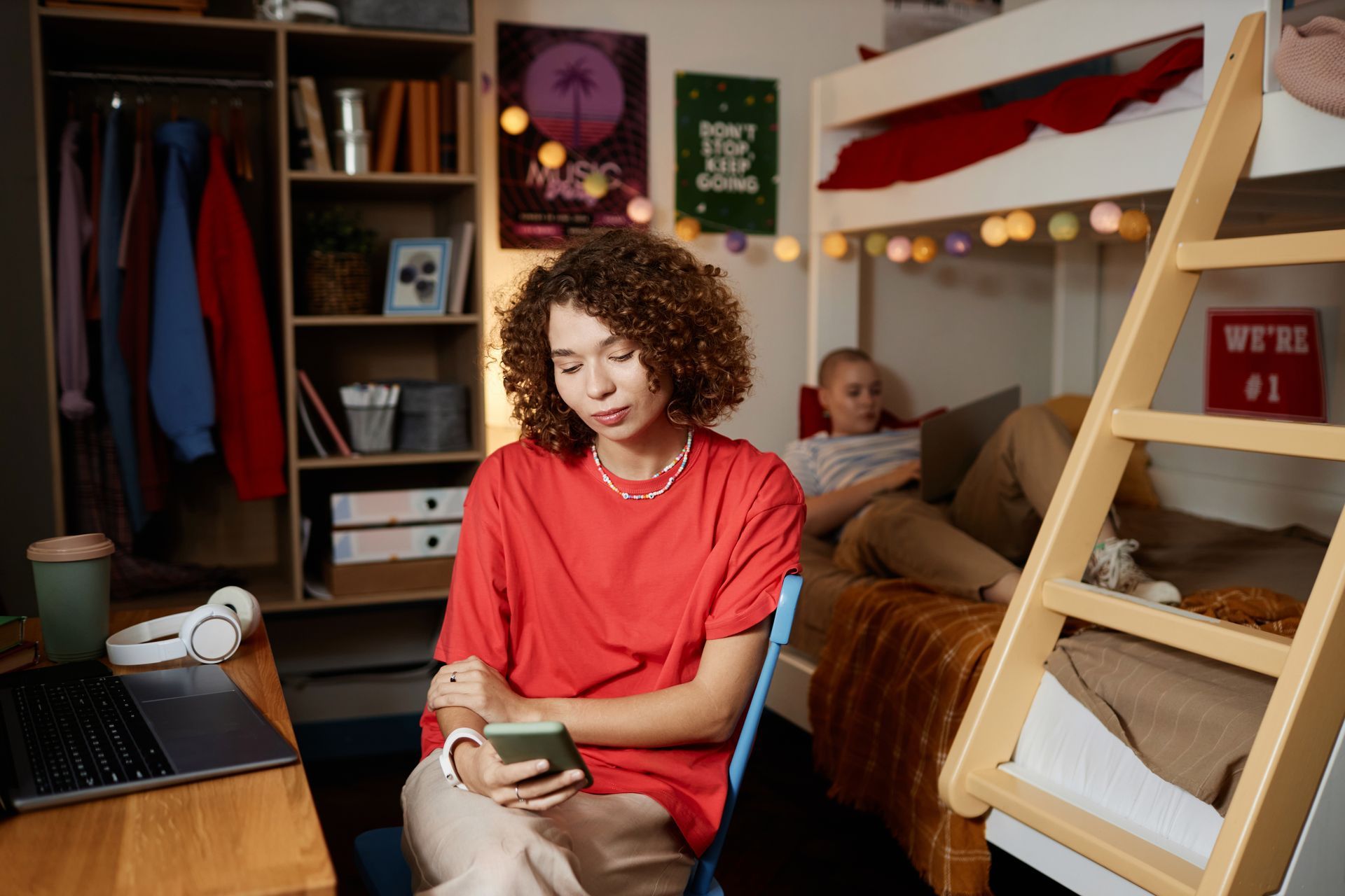 curly haired young woman using smartphone in college residence hall with bulk internet