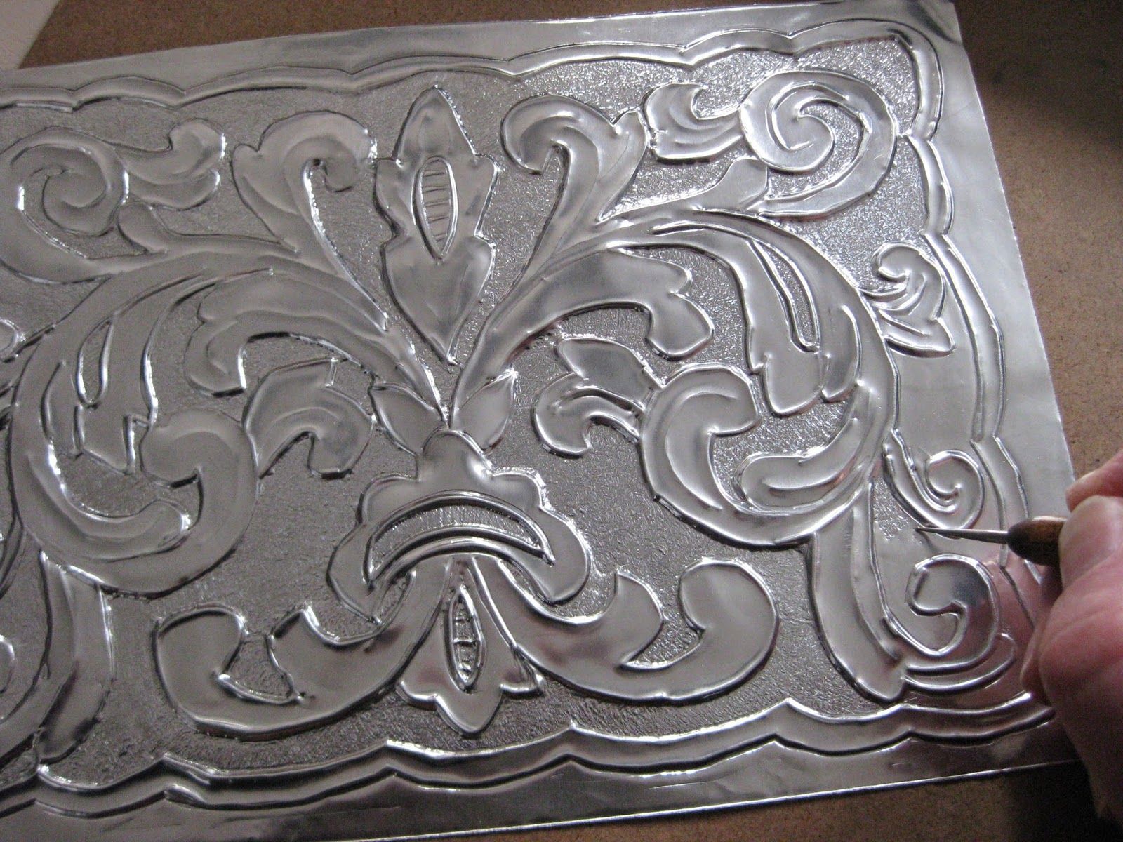 Tallado a mano de un elaborado diseño floral sobre una lámina de metal.