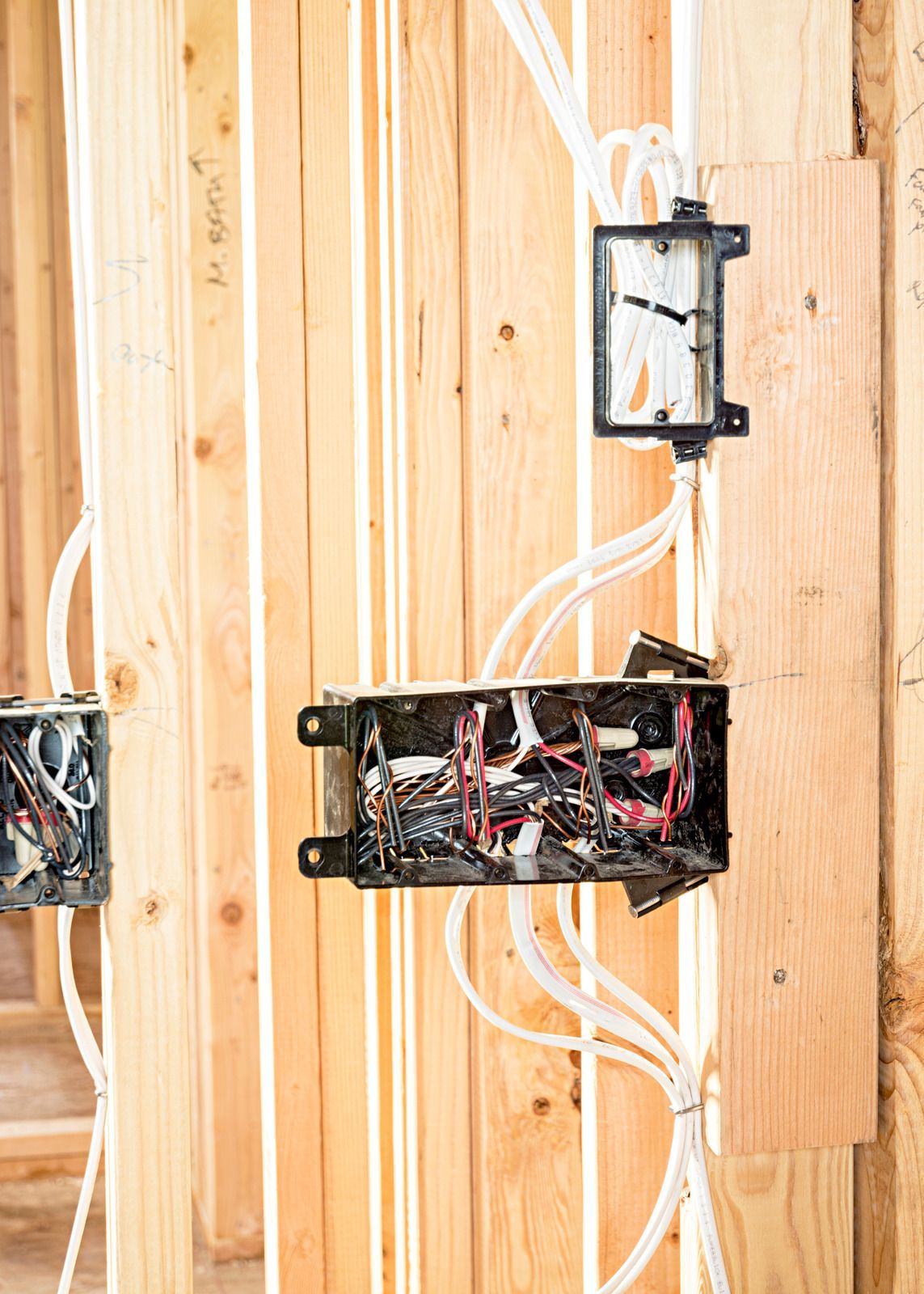 Electrical wiring and junction boxes installed on wood studs during construction.