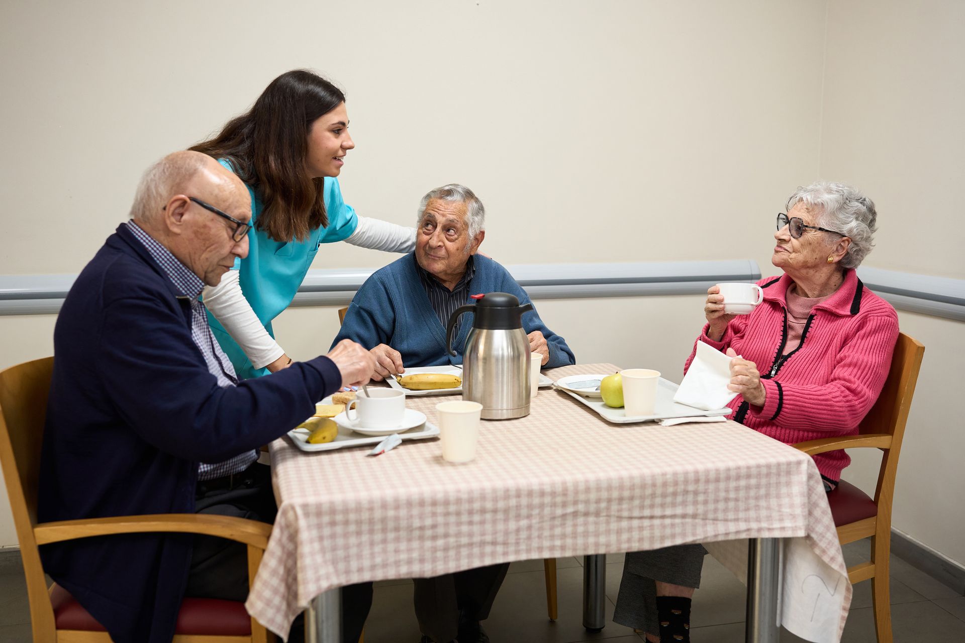 A group of elderly people are sitting around a table drinking coffee.
