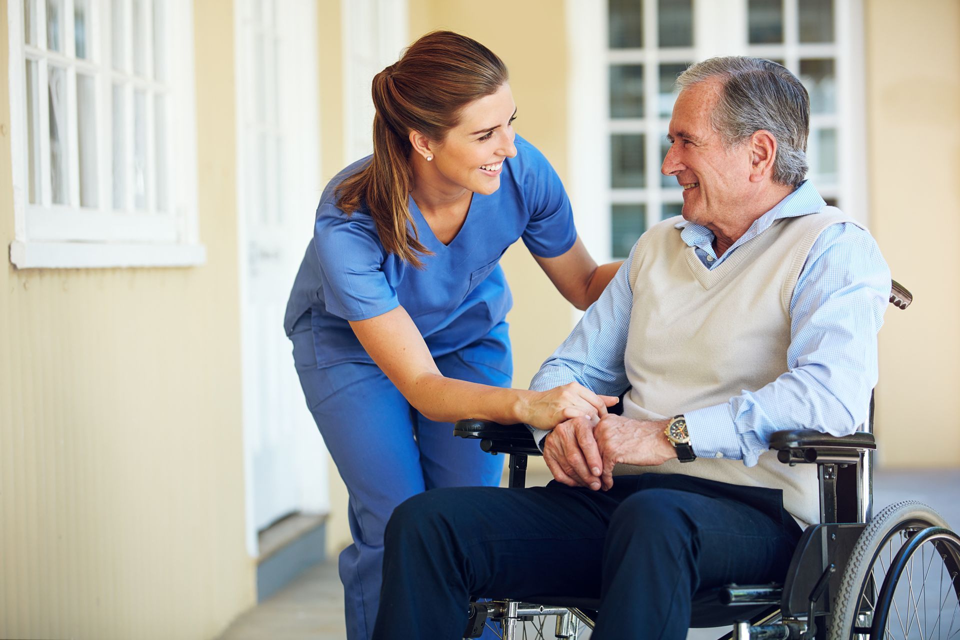A nurse helping an elderly to walk with wheelchair outside.