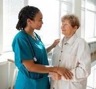 A woman is helping an elderly woman get dressed.