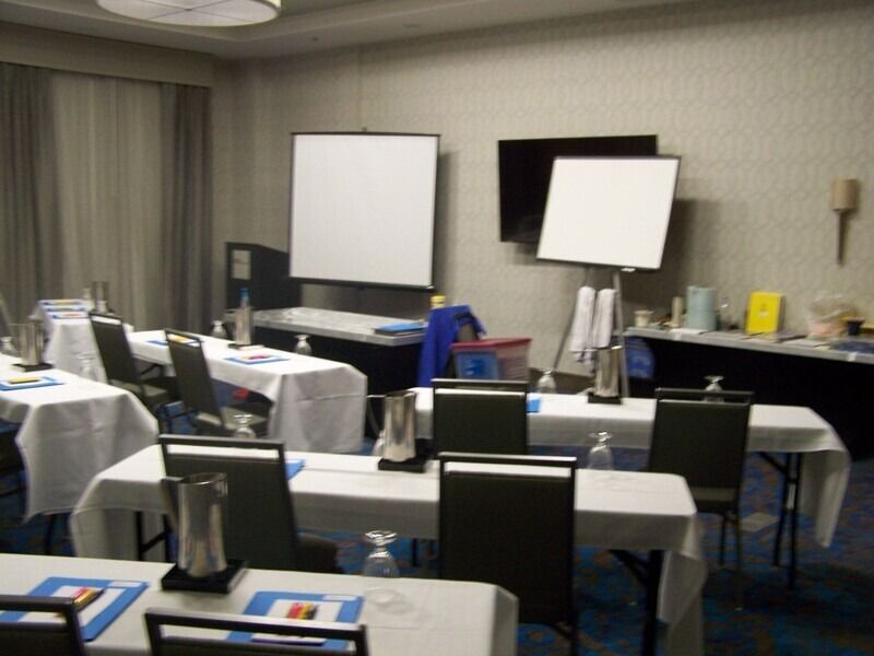 Meeting room with tables, chairs, screens, and presentation materials.