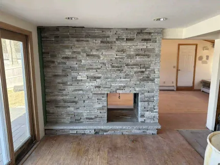 A living room with a stone fireplace and sliding glass doors.