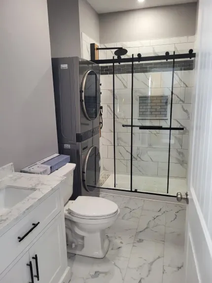 A bathroom with a toilet , sink , washer and dryer.