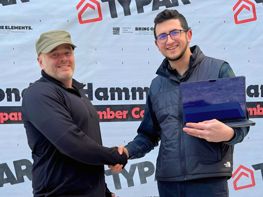 Two men shaking hands and one is holding a laptop