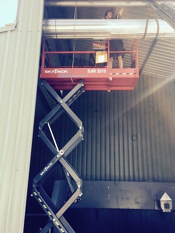 worker on lift installing industrial garage door