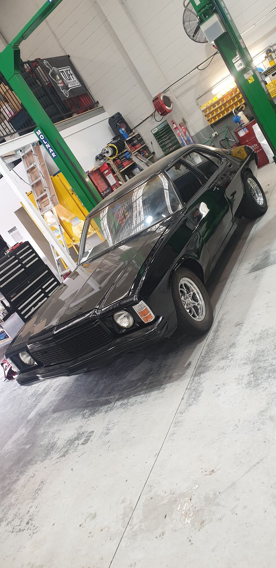 Black classic car in a workshop, parked near a green lift — Cartech Australia in Albury, NSW