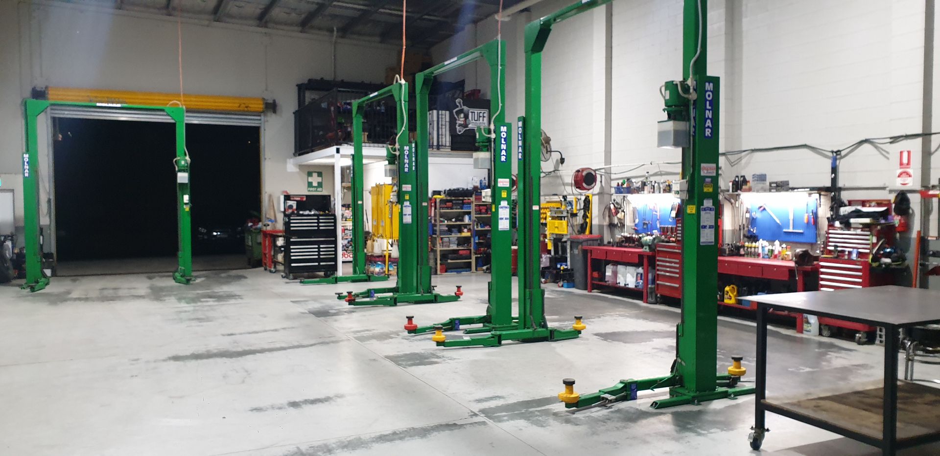 Inside a well-lit auto repair shop, there are green vehicle lifts — Cartech Australia in Albury, NSW
