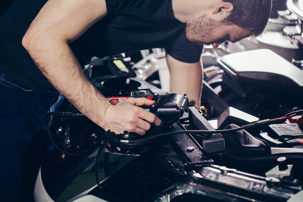 Mechanic Working on a Motorcycle Engine, Leaning Over the Vehicle — Cartech Australia in Wodonga, NSW