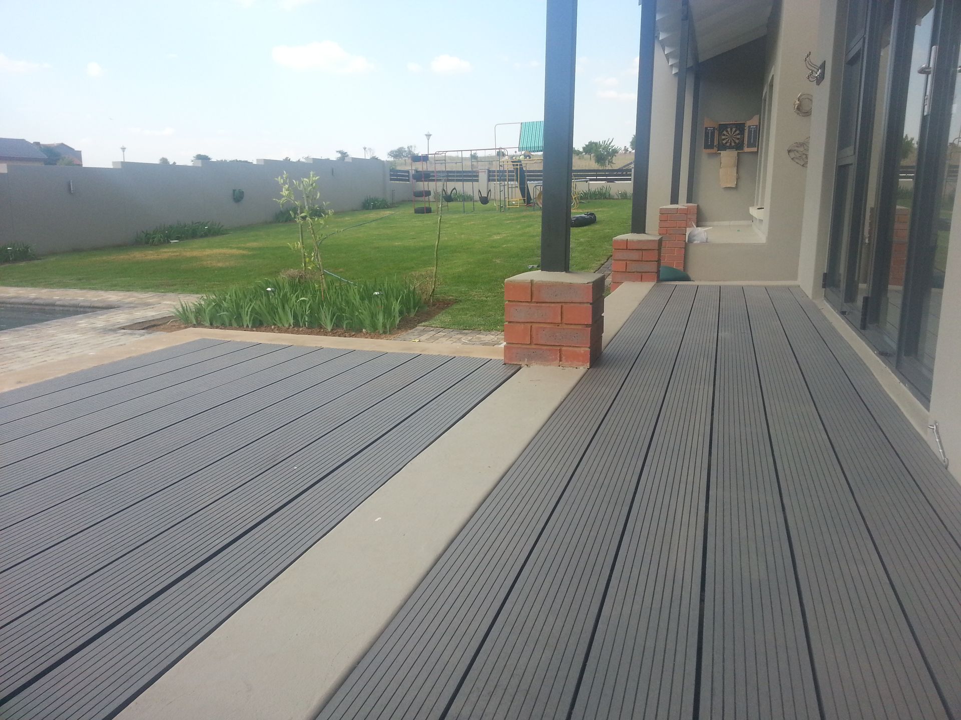 A gray deck with a brick pillar in the background