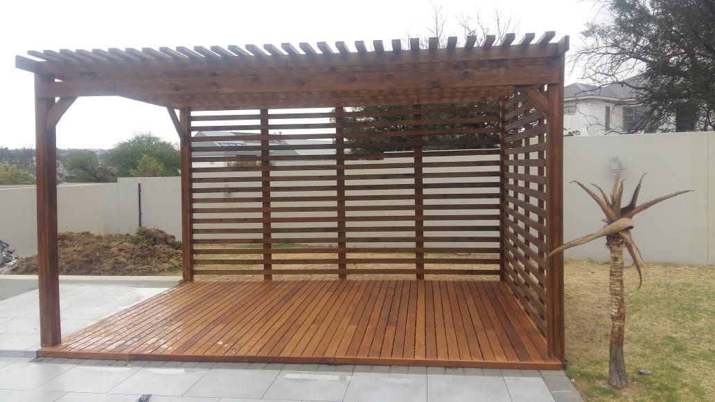 A wooden pergola is sitting next to a pool in a backyard.