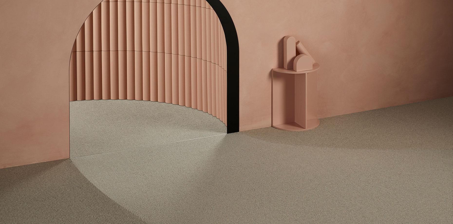 A room with a pink wall and a circular mirror on the floor.