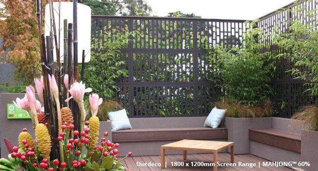 A patio with a fence and flowers in front of it