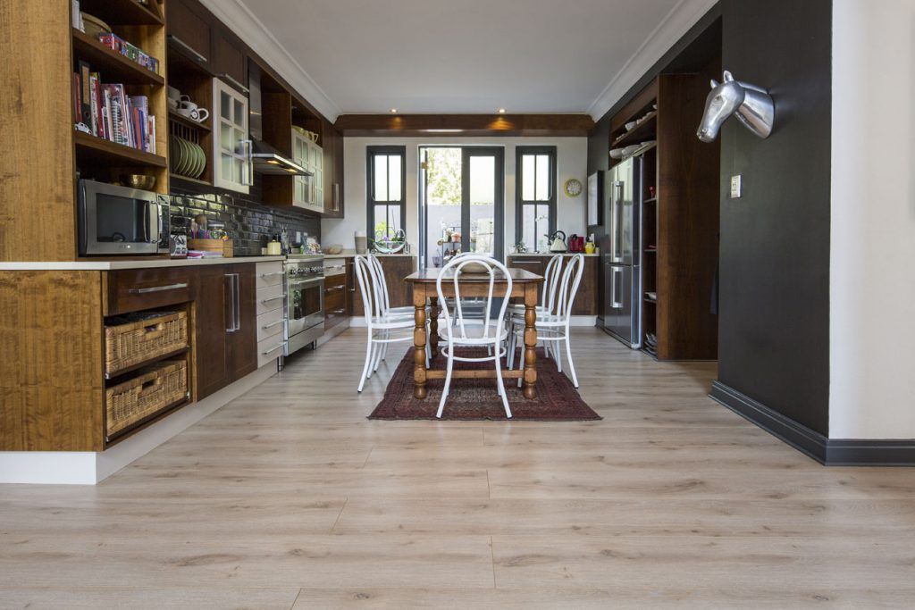 A kitchen and dining room with wooden floors and a table and chairs.