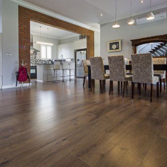 A dining room with a table and chairs and a kitchen in the background.