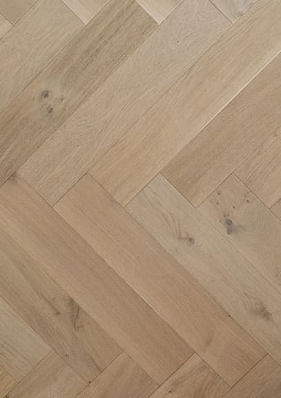 A close up of a wooden floor with a herringbone pattern.