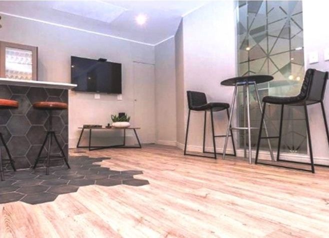 A living room with stools , a table and a flat screen tv.