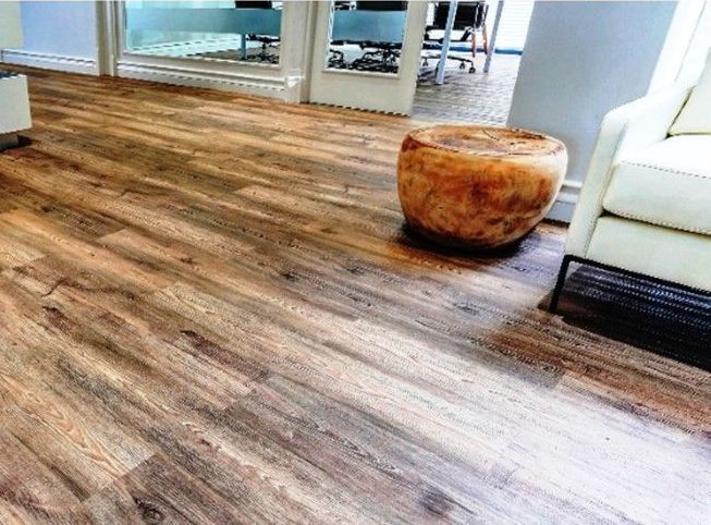 A living room with a wooden floor , a chair , and a table.