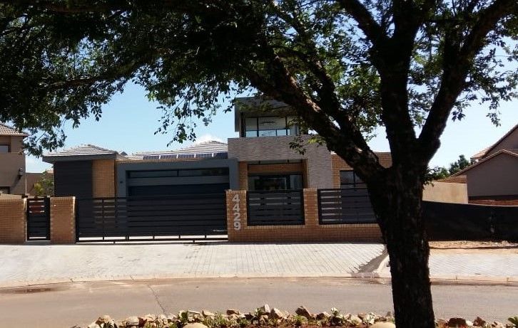 A house with a fence and a tree in front of it