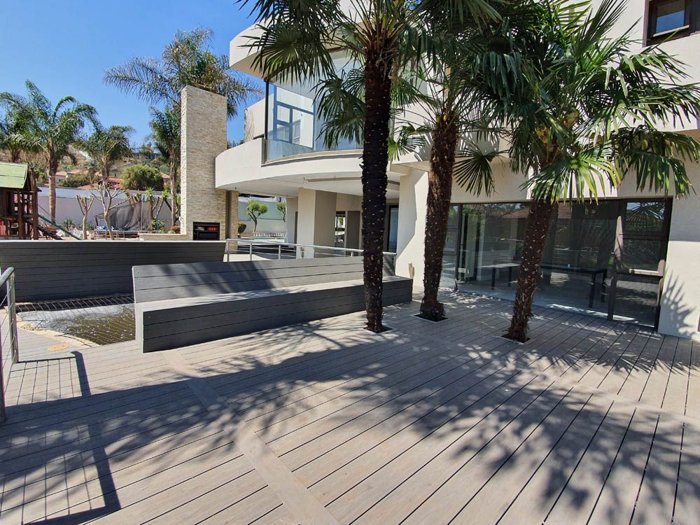 A wooden deck with palm trees in front of a building