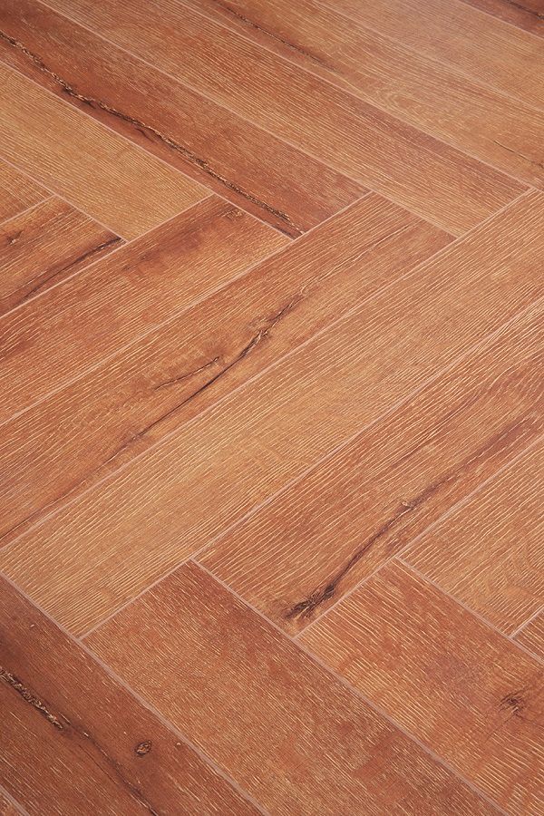 A close up of a wooden floor with a herringbone pattern.