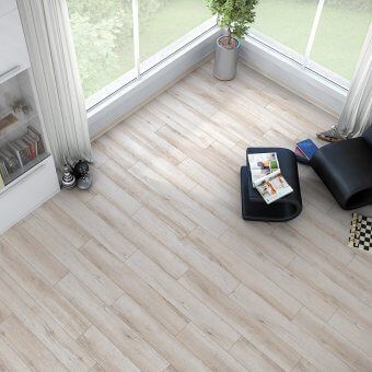 A living room with a wooden floor , a chair , a table and a window.