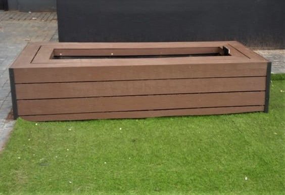 A wooden planter is sitting on top of a lush green lawn.