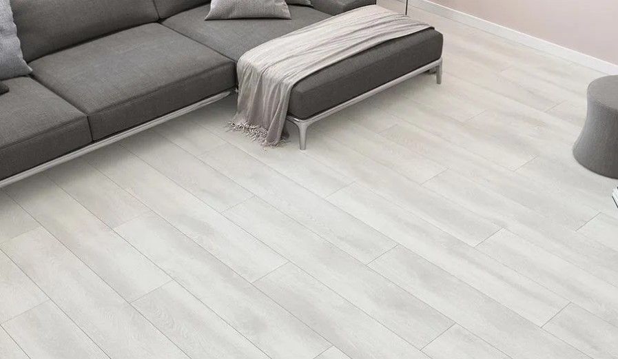 A living room with a couch and a white wooden floor.