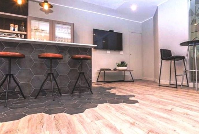 A living room with a bar and stools and a flat screen tv.