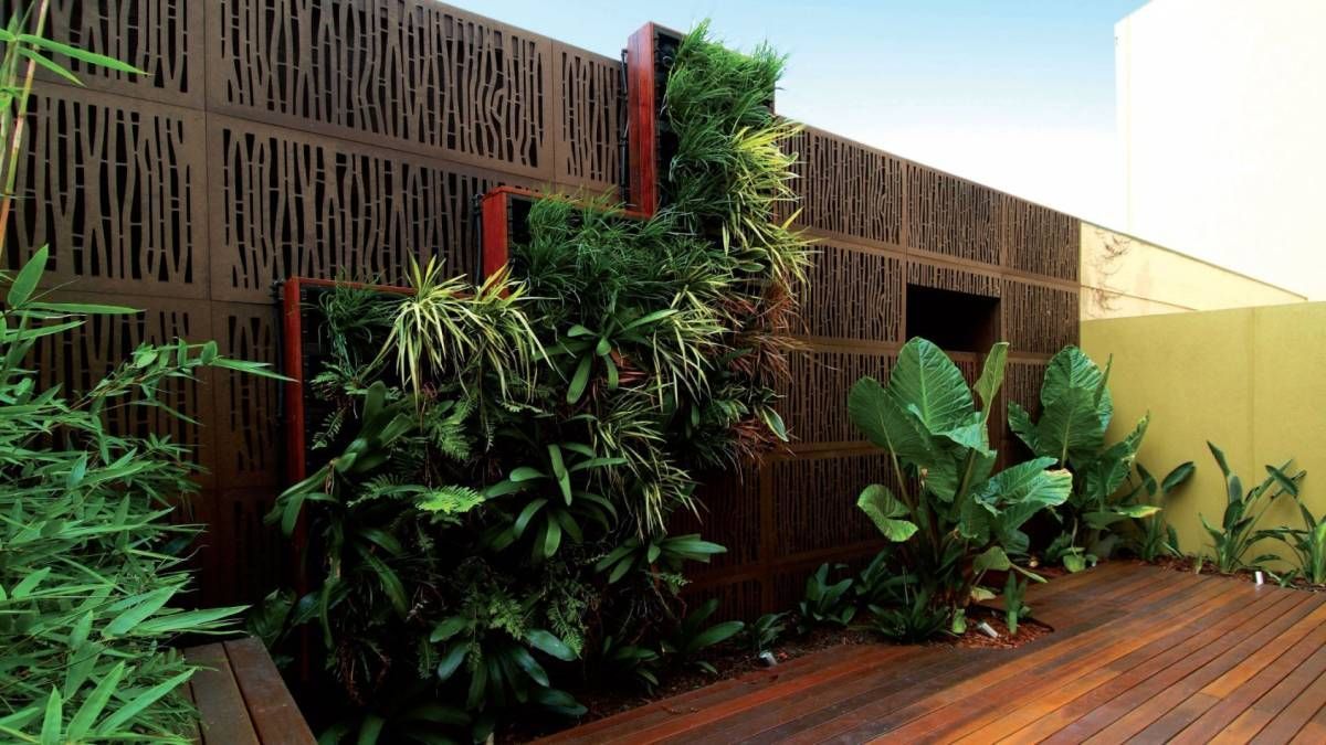 A wooden deck with a fence and plants in the background.
