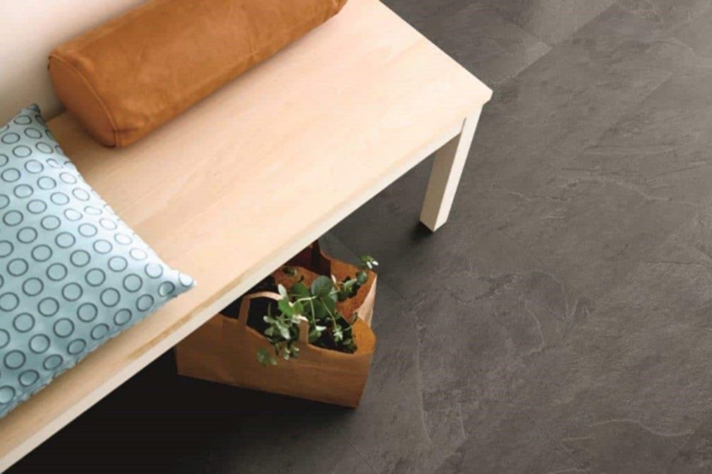 A wooden bench with two pillows and a potted plant on it.