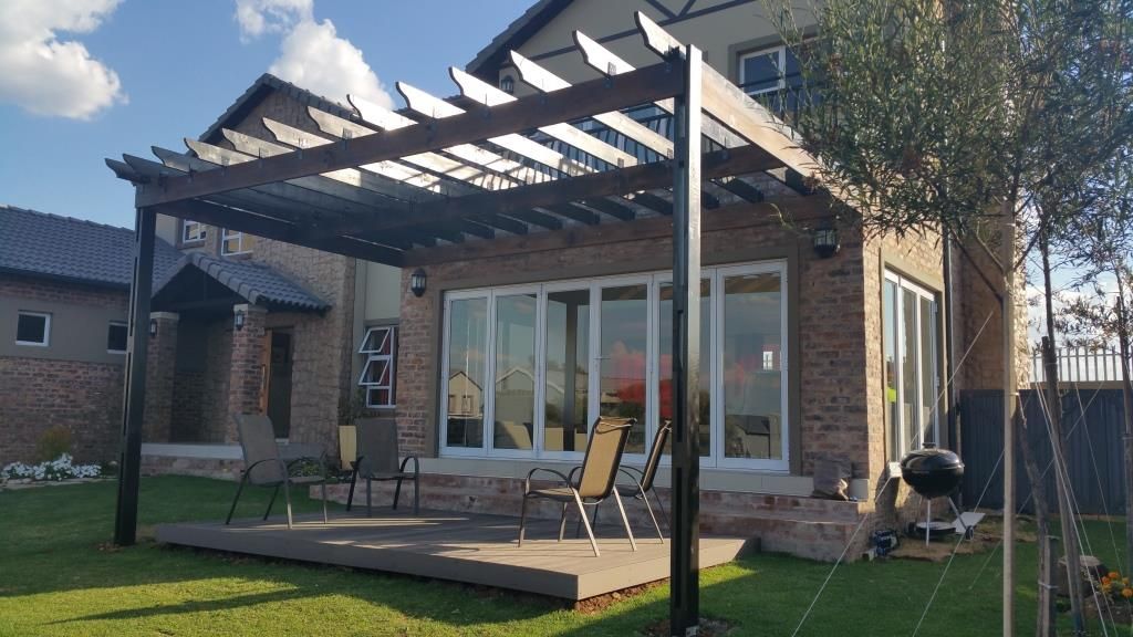 A house with a pergola and a deck in front of it.