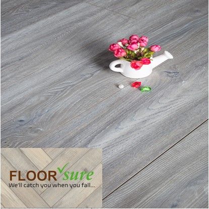 A vase of flowers sits on a wooden floor next to a sign that says floor sure