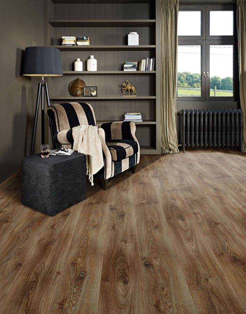 A living room with a wooden floor , a chair , a lamp , and shelves.