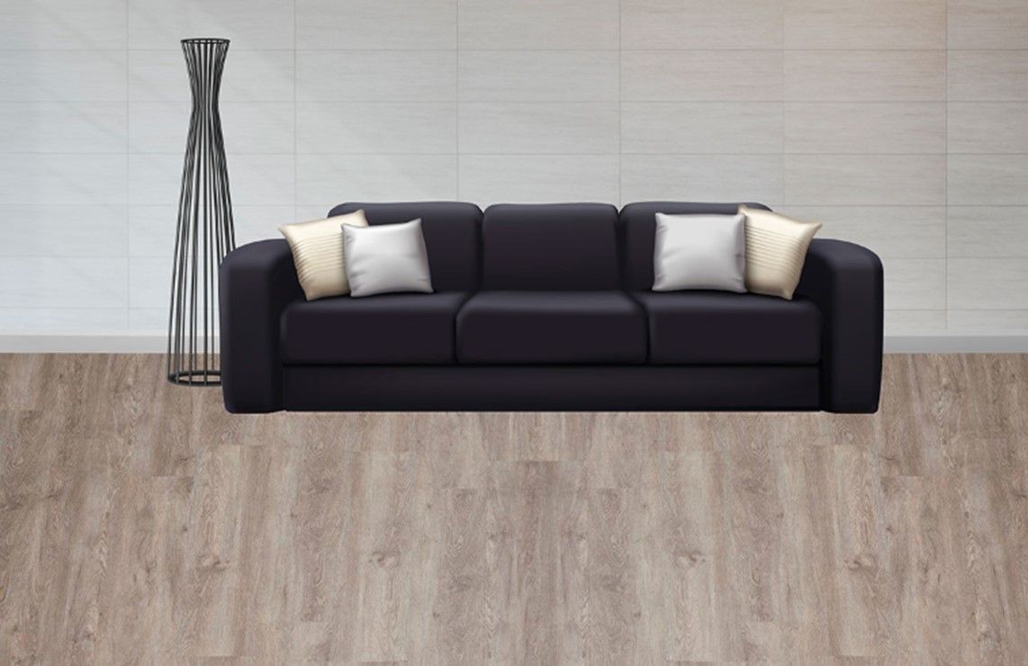 A black couch with white pillows is sitting on a wooden floor in a living room.