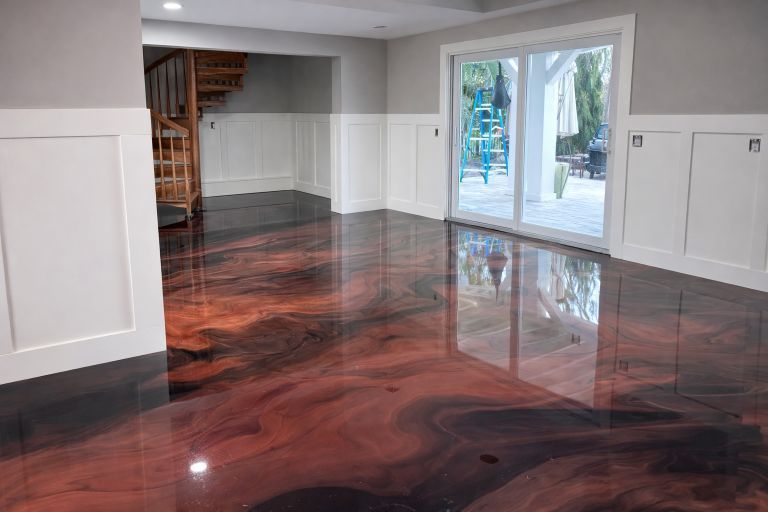 Room with glossy, swirled maroon and black epoxy floor; white paneled walls; sliding glass door to outside.
