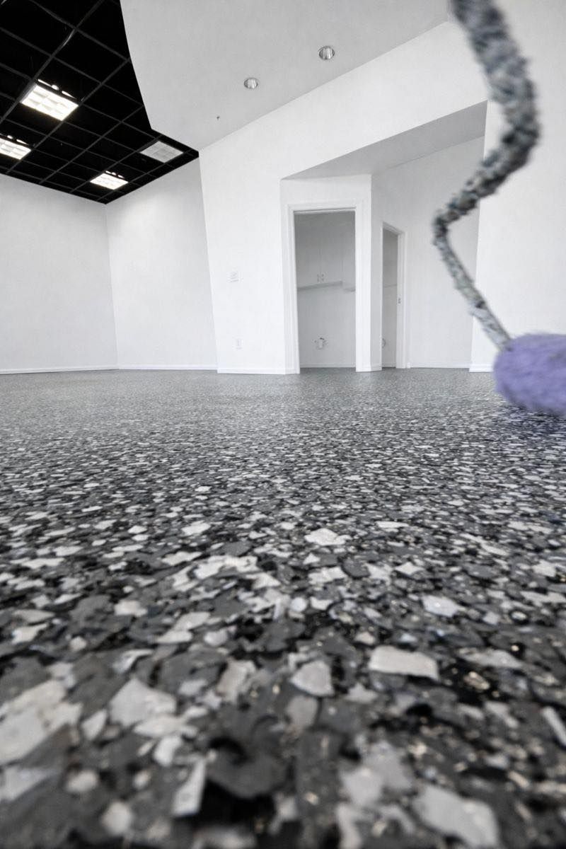 Empty room with speckled flooring and black ceiling, interior doorway.