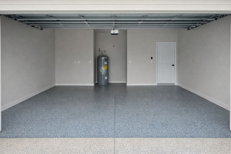 Empty garage with epoxy floor, water heater, and white door.