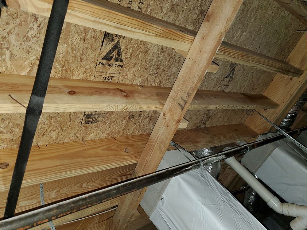 The ceiling of a house with wooden beams and pipes.