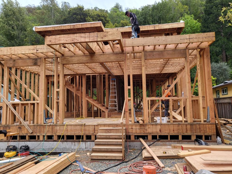 A man is working on the roof of a wooden house under construction.