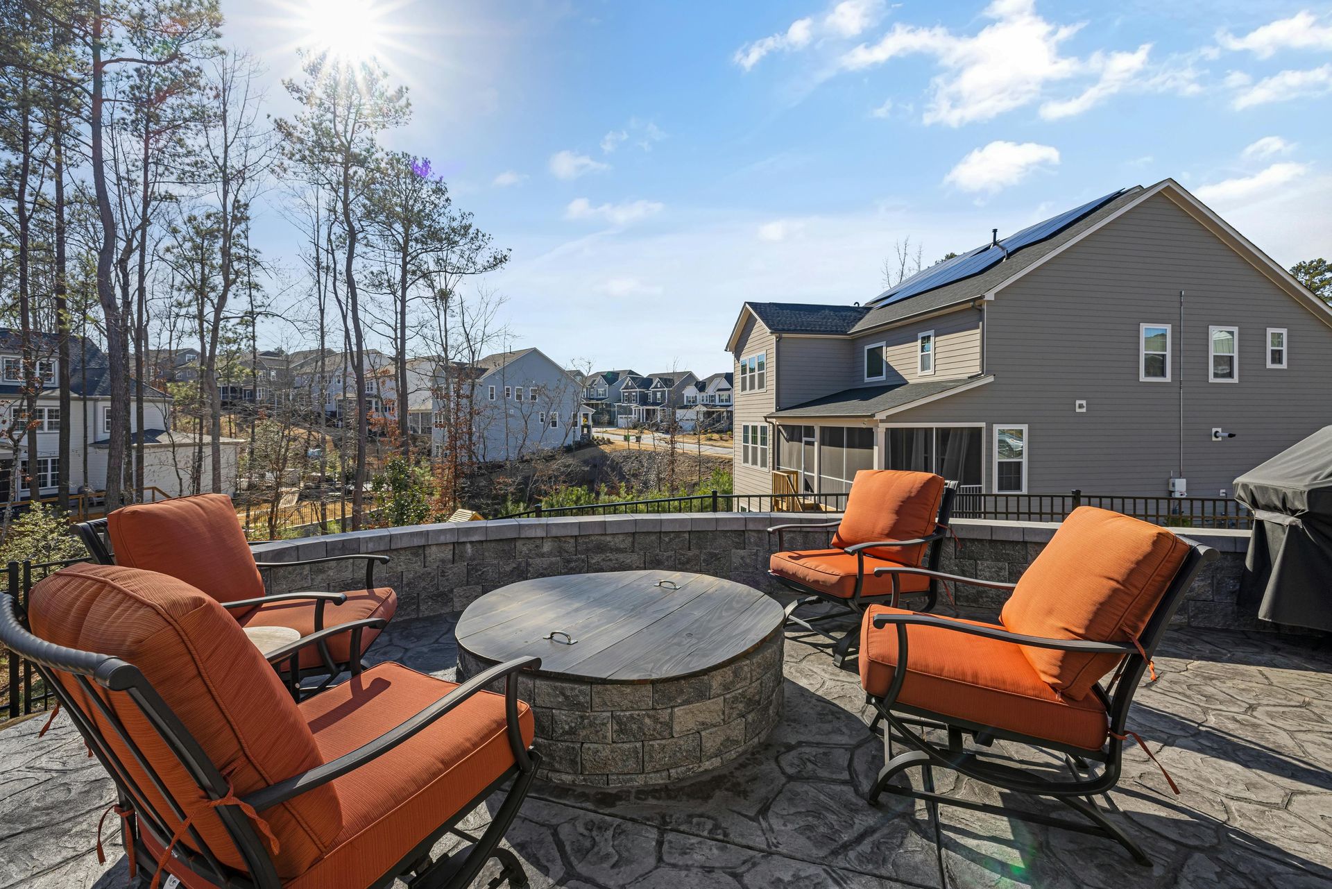 A fire pit with chairs and a table in front of a house.