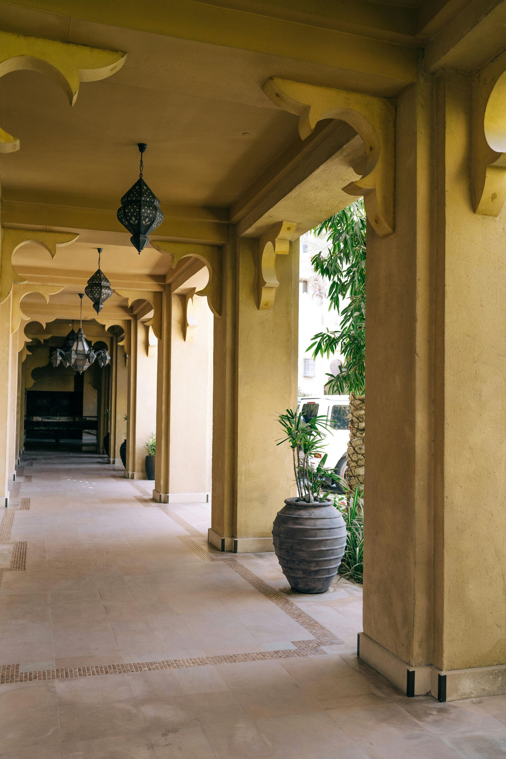 A long hallway with potted plants and lanterns hanging from the ceiling