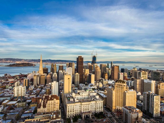An aerial view of a city with a lot of buildings and a body of water in the background.