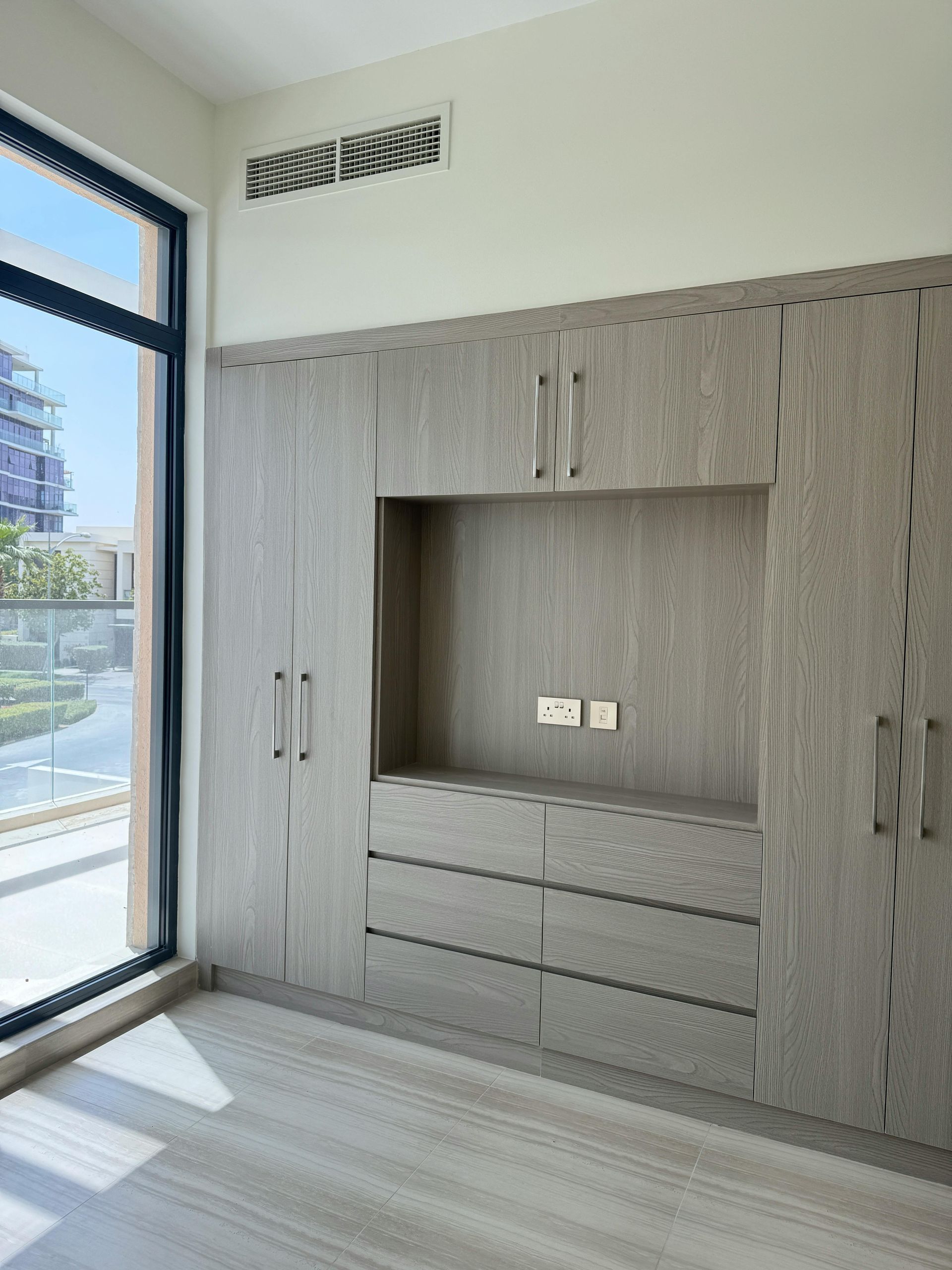 An empty room with a large window and a tv mounted to the wall.