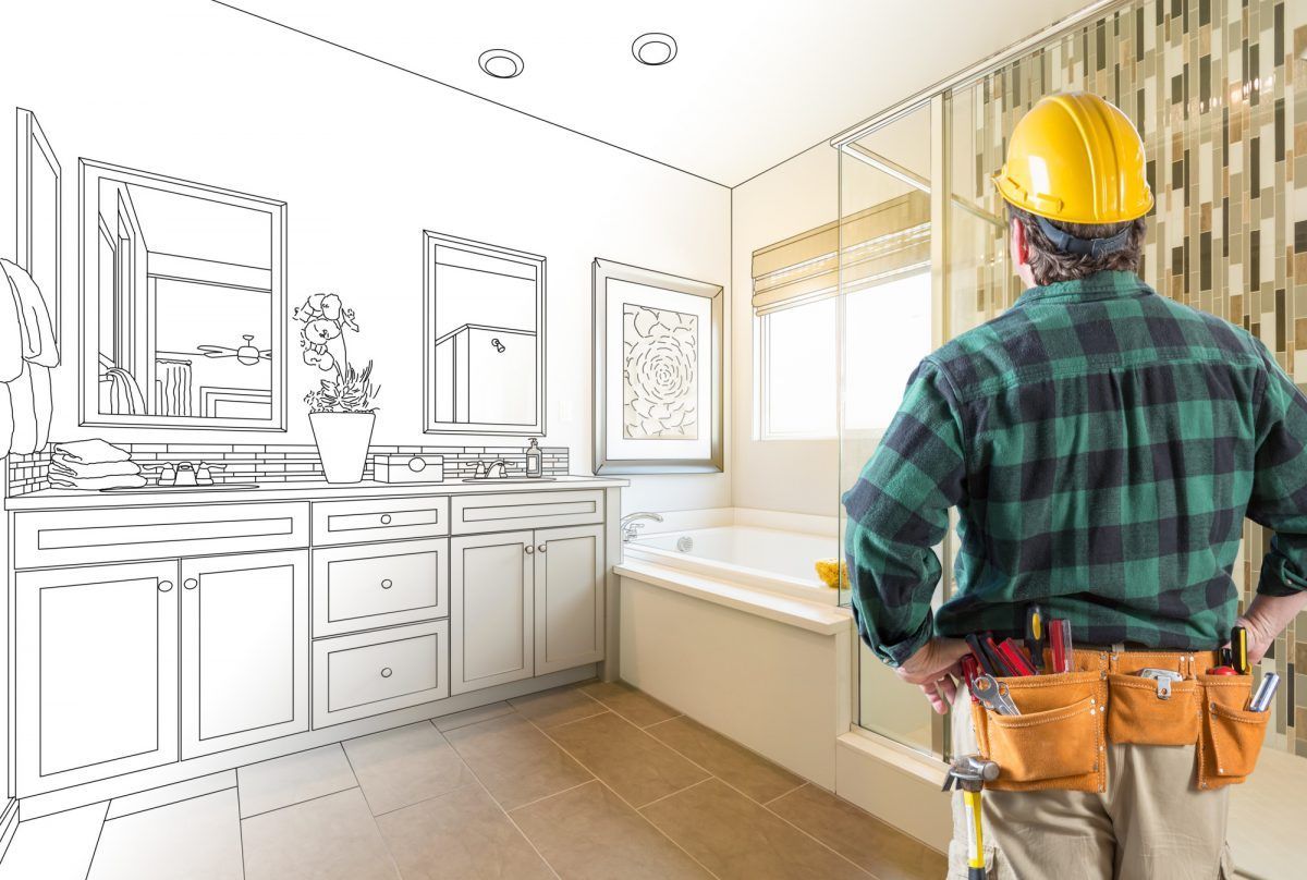 A construction worker is standing in a bathroom next to a drawing of the bathroom.
