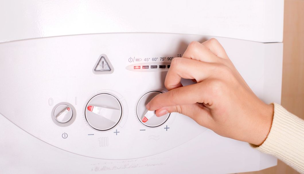 Regolazione manuale dei comandi a manopola di un elettrodomestico bianco su un pannello di controllo con icone di temperatura