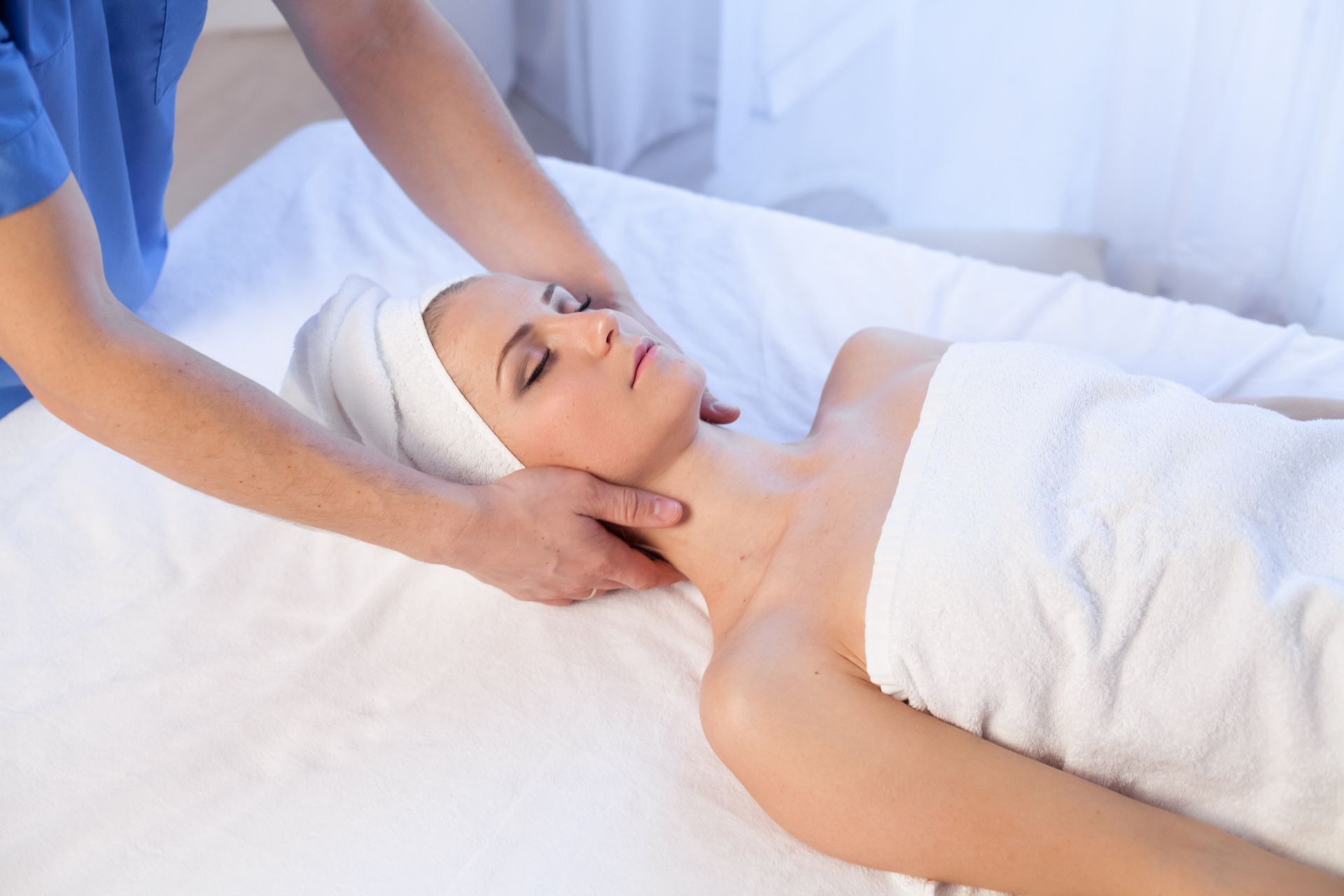 A person is receiving a neck massage on a white massage table - Thames, NZ - Thai Classic Massage Thames