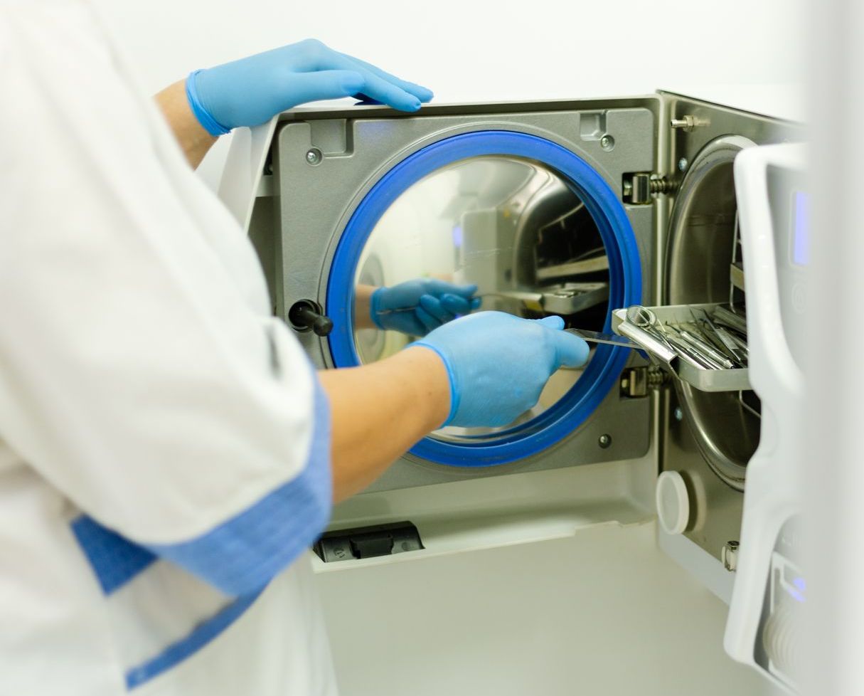 A person wearing blue gloves is working on a machine